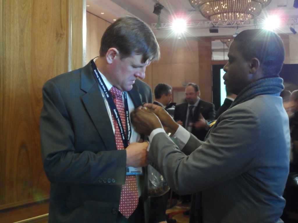 Gilbert Kuepouo fixing a pin onto a government delegate’s lapel.